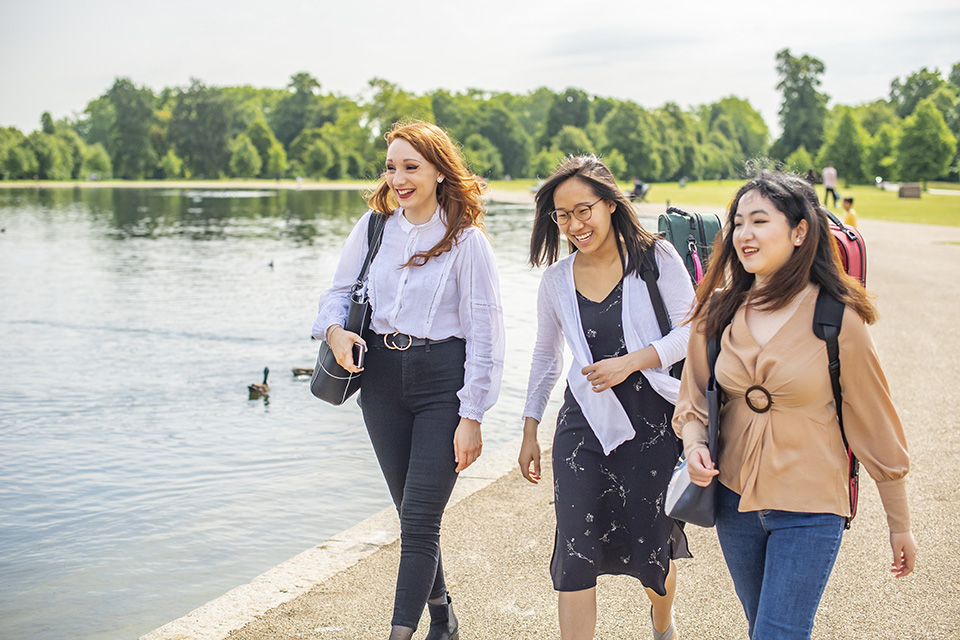 Three RCM students walking past a lake in a park